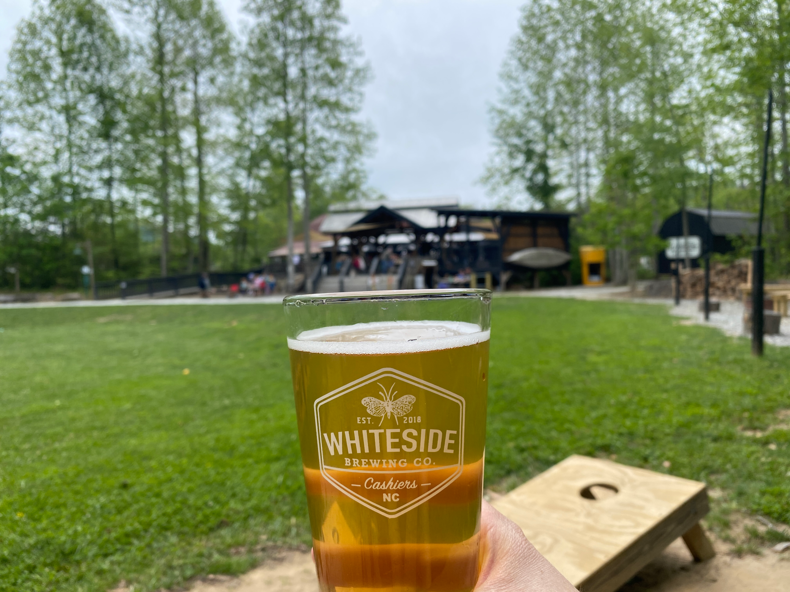 Glass of beer at Whiteside Brewing Company in Cashiers NC with outdoor patio in background